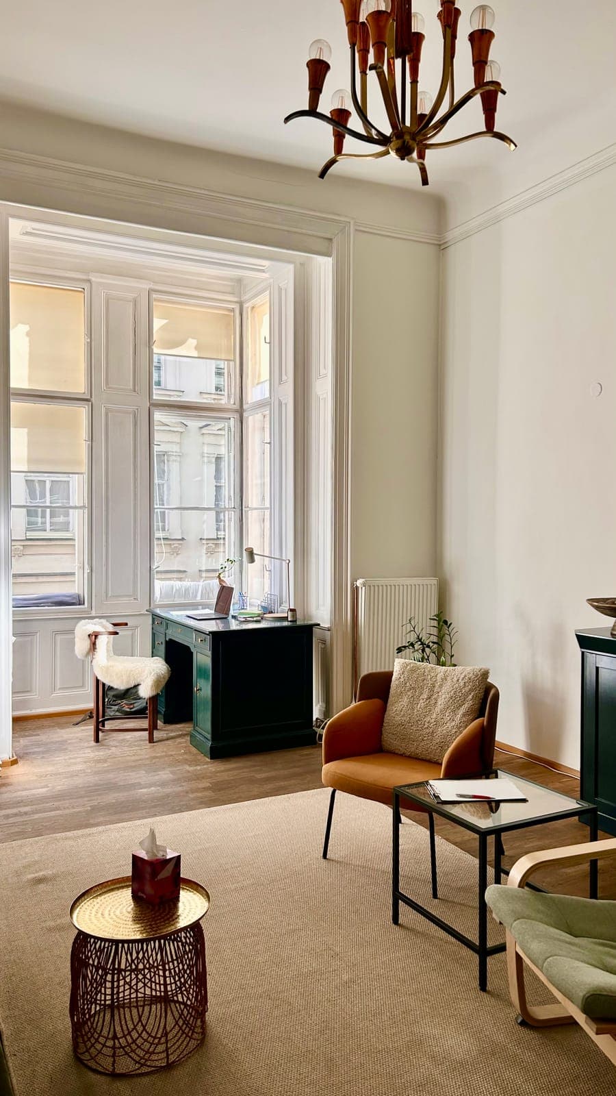 The bright window bay with a desk, beside an armchair and a low table